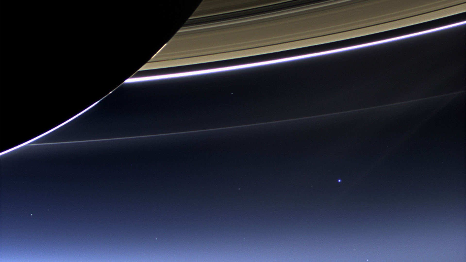 Saturnringe aufgenommen von der Raumsonde Cassini Juli 2013. Im Hintergrund rechts unter den Ringen die Erde als leuchtender Punkt.