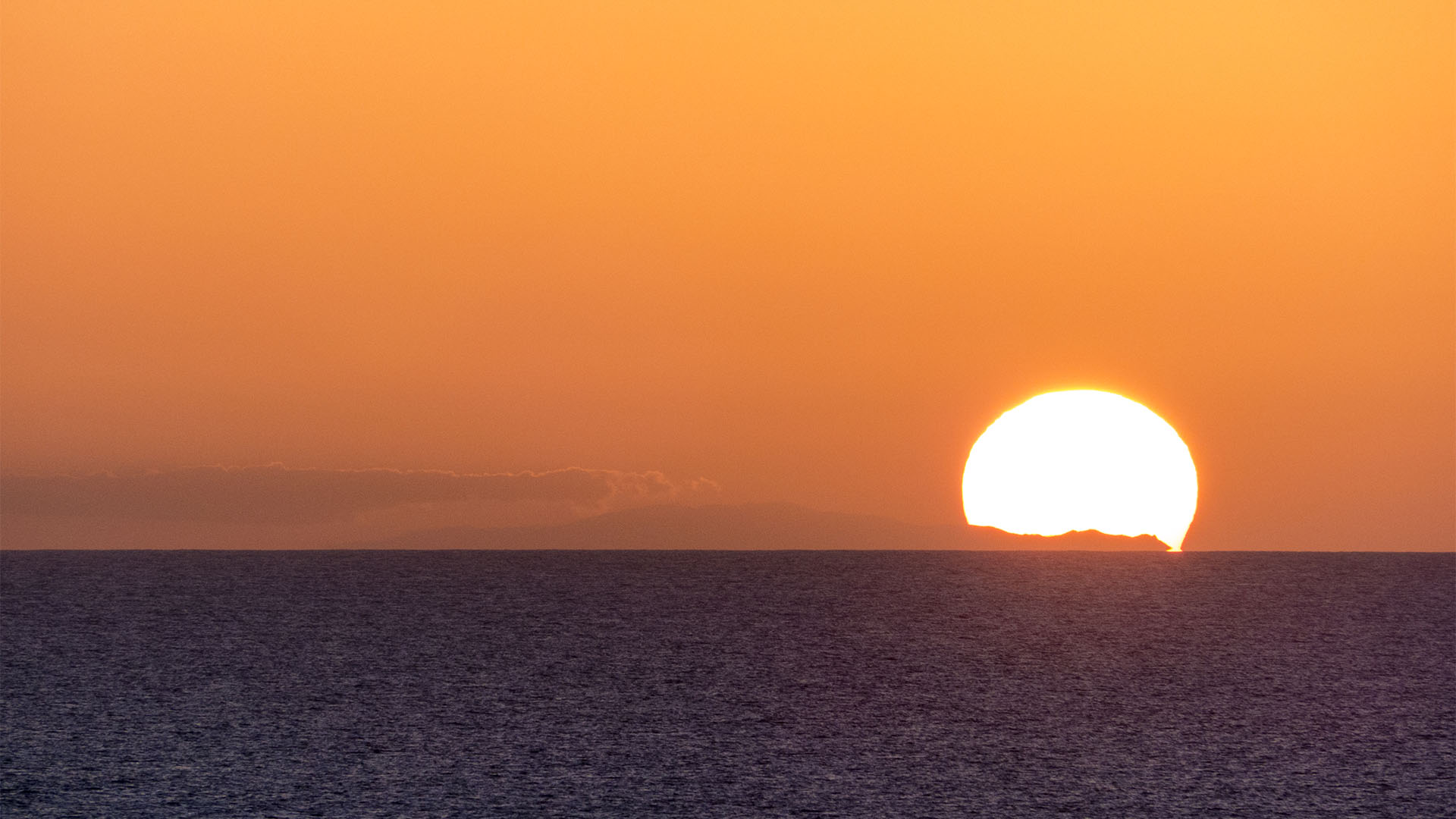 Sonnenuntergang auf Fuerteventura – die 120 Km entfernte Insel Gran Canaria zeichnet ihr Profil gegen den glühenden Himmel.