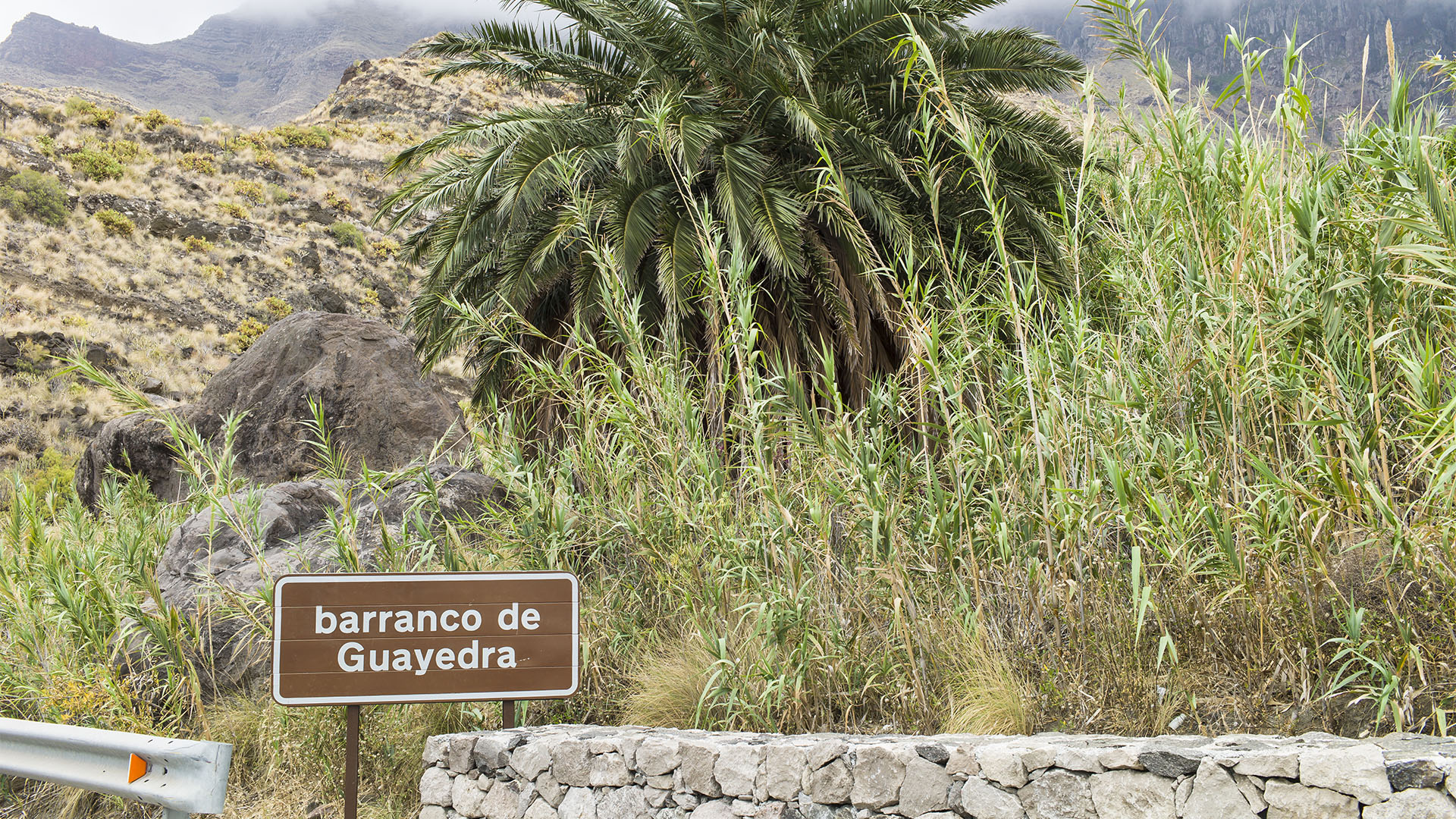 Aus Süden kommend führt vor dem Schild Barranco de Guayedra kaum sichtbar eine kleine Piste zum Playa de Guayedra hinab.