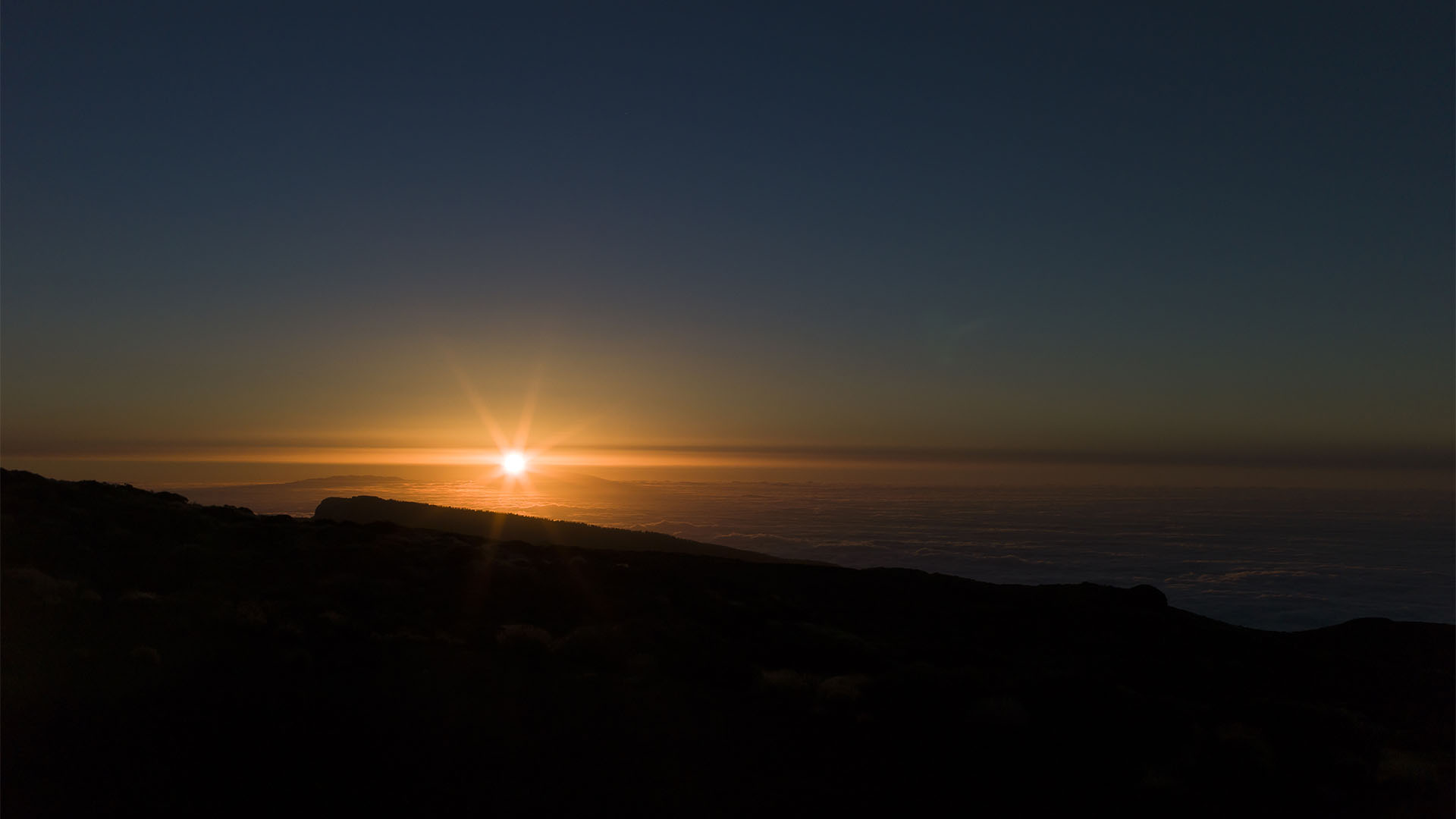 Sonnenuntergang Teide: Die Sonne versinkt hinter den Bergen der insel La Palma, die aus dem Wolkenmeer ragen. Blick vom Montaña de la Carniceria 2.367 m.