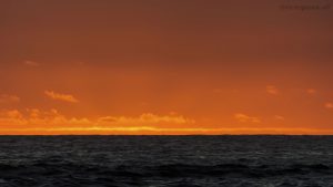 Die untergehende Sonne lässt den Sahara Staub in der Luft orange aufleuchten.