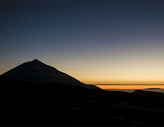 Neben der Silouhette des Teide versinkt die Sonne im Wolkenmeer aus dem die Gebirgszüge der Insel La Palma ragen. Blick vom Montaña de la Carniceria 2.367 m.