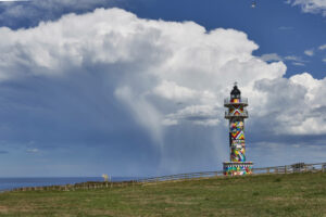 Faro de Ajo im Design des kantabrischen Künstlers Okuda San Miguel vor den Resten einer Gewitterzelle.